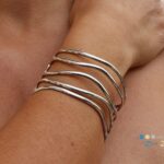 Brede zilveren armband bestaande uit ovale draden die een speels patroon volgen